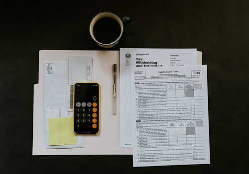 open file folder with tax documents and phone with a cup of coffee above