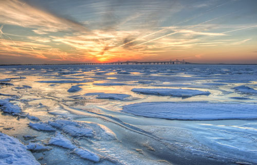 chesapeake bay with bridge in background and ice on top of water