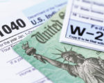 1040 income tax form and w-2 wage statement with a federal Treasury refund check. Closeup with selective focusing.